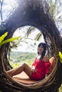 A female tourist is sitting on a large bird nest on a tree at Bali island Royalty Free Stock Photo