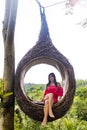 A female tourist is sitting on a large bird nest on a tree at Bali island Royalty Free Stock Photo