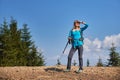 Female blond backpacker hiking on stone road.