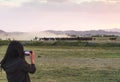 Female tourist take photograph of herd of wild horse