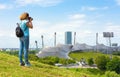 Female tourist takes photos of Olympic park in summer, Munich, Germany