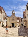 Female tourist taking photo of mall church on square of small urban village of Stari grad on Hvar island in Croatia Royalty Free Stock Photo