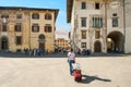 A female tourist traveling solo and pulling a luggage suitcase on wheels in the historic center of Pisa, Italy