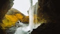 Female tourist walk on pathway visit famous Kvernufoos waterfall landmark. Yellow grass hills on Kvernufoss waterfall. Majestic