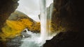 Female tourist walk on pathway visit famous Kvernufoos waterfall landmark. Yellow grass hills on Kvernufoss waterfall. Majestic