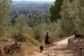 A female tourist walking with her dog on a path among olive trees in the Tuscany, Vinci village is in the background Royalty Free Stock Photo