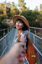 A female tourist walks across a bridge over the river. A young woman walks along a suspension bridge across a river in front of an Royalty Free Stock Photo