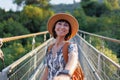 A female tourist walks across a bridge over the river. A young woman walks along a suspension bridge across a river in front of an Royalty Free Stock Photo