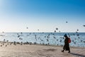 A female tourist wearing black hijab catching grey doves at the Jeddah Corniche coastal resort park near red sea in Jeddah, Royalty Free Stock Photo