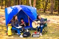 Female tourists camping and playing guitar in the forest