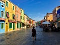 A female tourists exploring the colourful streets of Burano, Italy, on a beautiful quiet summer morning.