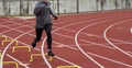 Female track runner running over yellow mini hurdles in winter outdoor