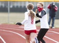 Female track runners exchanging the baton during a relay race wearing face masks Royalty Free Stock Photo