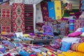 Female trader at Souq Waqif market in Doha, with multicolour carpets, kilims and other items. Doha, Qatar
