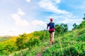 A female trail runner, dressed for runners, sportswear, is practicing on a dirt path in a high mountain forest. with a happy mood