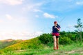 A female trail runner, dressed for runners, sportswear, is practicing on a dirt path in a high mountain forest. with a happy mood