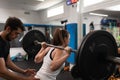 A female trainee lifting weights while being watched by her coach