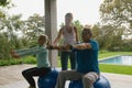 Female trainer assisting active senior couple to exercise with dumbbell in the porch Royalty Free Stock Photo