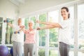 Female trainer assisting senior couple in performing exercise Royalty Free Stock Photo