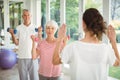 Female trainer assisting senior couple in performing exercise Royalty Free Stock Photo