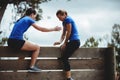 Female trainer assisting woman to climb a wooden wall Royalty Free Stock Photo