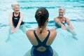 Female trainer with senior women exercising in swimming pool