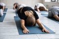 Female trainer showing child restorative pose on floor mat.