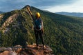 A female traveler with a backpack stands on the edge of the mountain, a rear view.