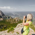 Female traveler enjoying the views from the mountains of Montserrat in Spain and makes a photo