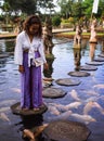 Solo Female Traveler Feeding Koi Fish on Stepping Stones around Koi Fish at Main fountain at Tirta Gangga, Bali
