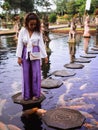 Solo Female Traveler Feeding Koi Fish on Stepping Stones around Koi Fish at Main fountain at Tirta Gangga, Bali