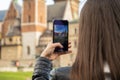 Female traveler in historical places looks around courtyard of landmark and shoots short video on phone. Unrecognizable