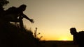 Female traveler holds the hand of a male traveler helping to climb top of the hill. Tourists climb the mountain at