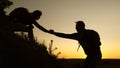 Female traveler holds the hand of a male traveler helping to climb top of the hill. Tourists climb the mountain at