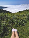 Female traveler legs in white socks with mountains landscapes and clouds on the background