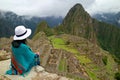 Female Traveler Sitting on the Cliff Looking at the Inca ruins of Machu Picchu, Peru