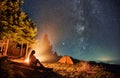 Female traveler sitting near campfire under night starry sky. Royalty Free Stock Photo