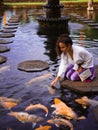 Solo Female Traveler Feeding Koi Fish at Main fountain at Tirta Gangga, Bali