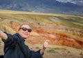 Female traveler takes a selfie sitting on hill on the background of Martian landscapes in Altai mountains. Young girl smiles the Royalty Free Stock Photo