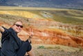 Female traveler takes a selfie sitting on hill on the background of Martian landscapes in Altai mountains. Young girl smiles the Royalty Free Stock Photo