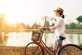 Female traveler weared light summer clothes and straw hat having early morning bicycle walk in Ayutthaya historical park, Thailand