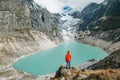 Female trekker dressed bright red jacket on the rock enjoying a glacier falling in high altitude Sabai Tso glacial lake cca 4350m