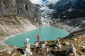 Female trekker dressed bright red jacket on the rock enjoying a glacier falling in high altitude Sabai Tso glacial lake cca 4350m