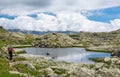 Female trekker walking along mountain lake. Royalty Free Stock Photo