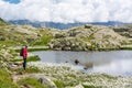 Female trekker walking along mountain lake. Royalty Free Stock Photo