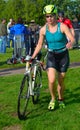 Female triathlete at end of cycling stage with bicycle.