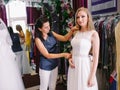 Female trying on wedding dress in a shop with women assistant. Royalty Free Stock Photo