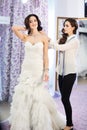 Female trying on wedding dress in a shop with women assistant. Royalty Free Stock Photo