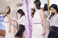 Female trying on wedding dress in a shop with women assistant. Royalty Free Stock Photo