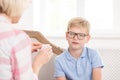 Female tutor asking her pupil to translate word, writed on card. Young boy trying to remeber translation. They are